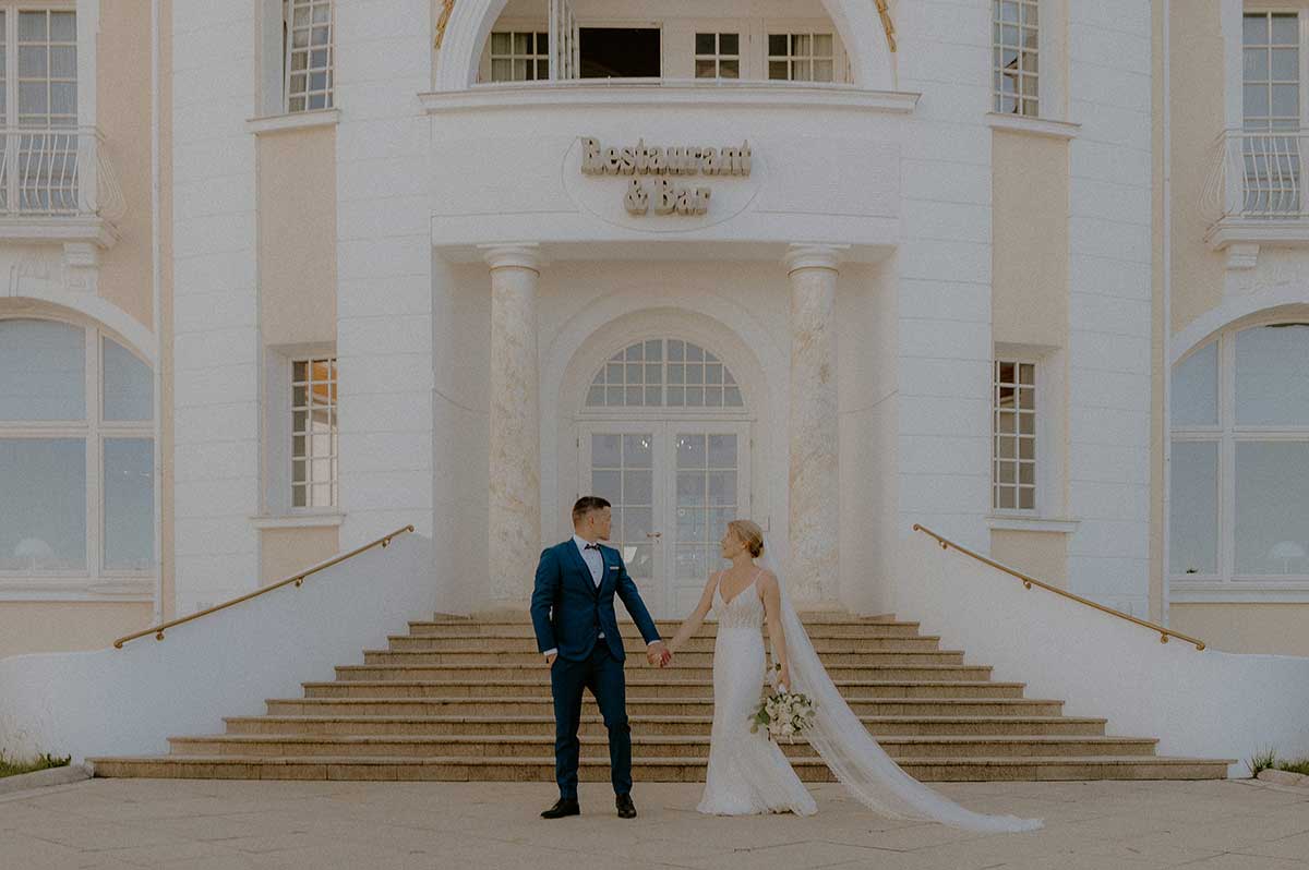 Braut und Bräutigam stehen Hand in Hand vor ihrer Hochzeitslocation – freie Trauung auf Rügen