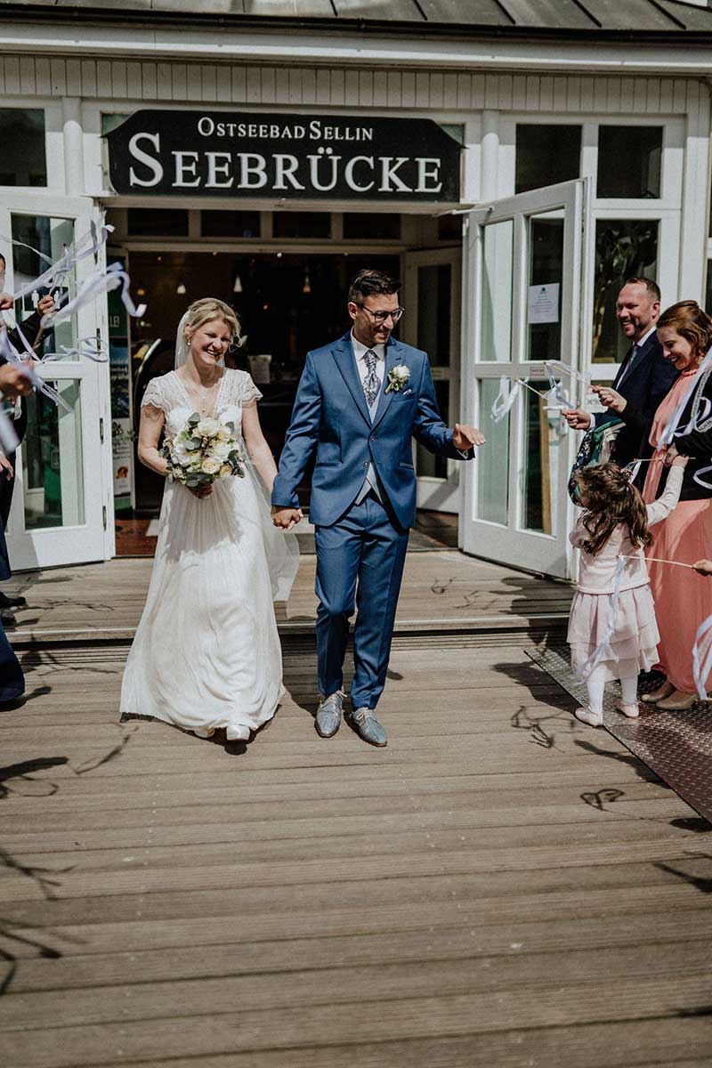 Glückliches Brautpaar nach der freien Trauung an der Seebrücke Sellin auf Rügen – emotionaler Moment beim Auszug aus der Trauung