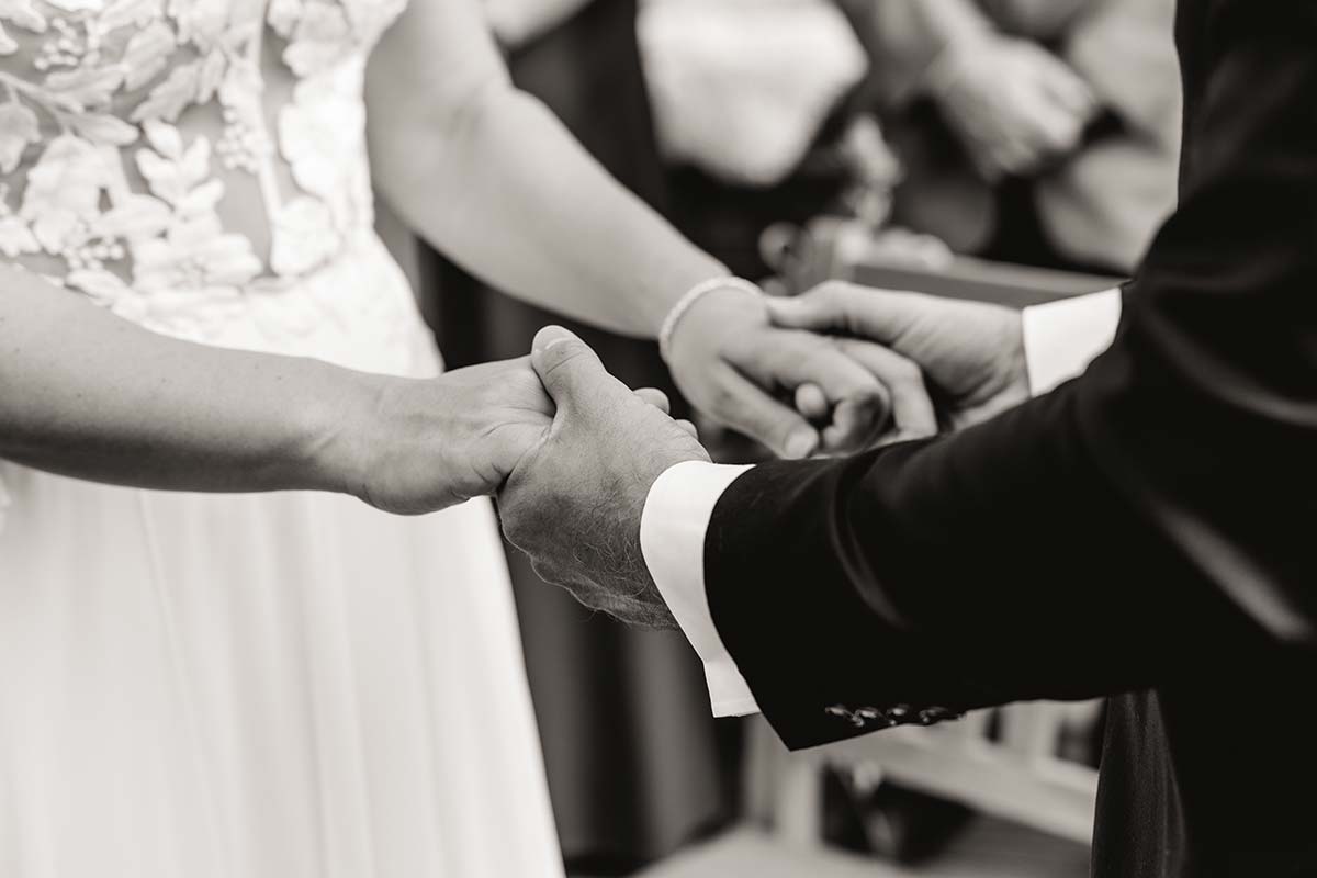 Braut und Bräutigam halten sich während der freien Trauung auf Rügen liebevoll an den Händen