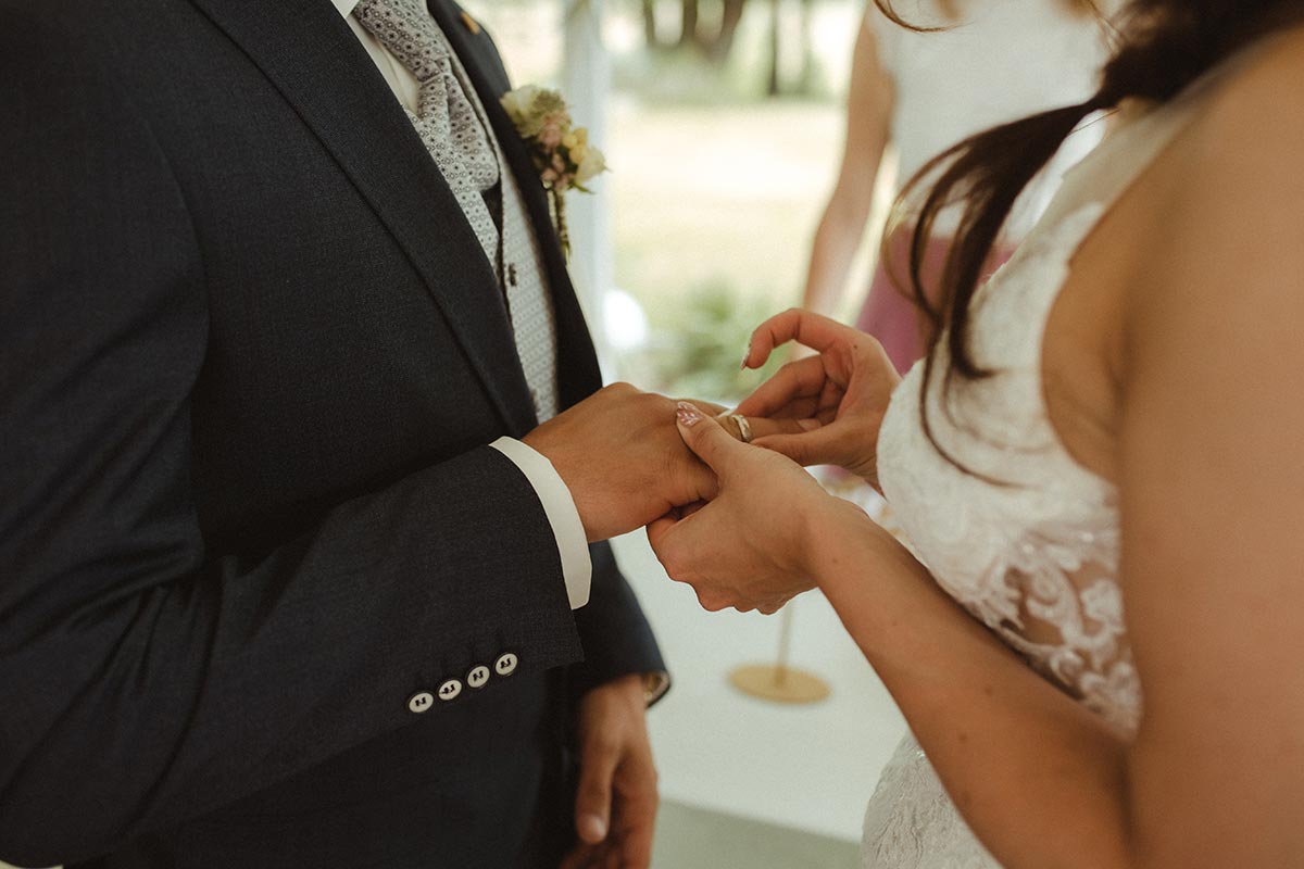 Nahaufnahme, wie die Braut dem Bräutigam bei einer freien Trauung auf Rügen den Ehering ansteckt