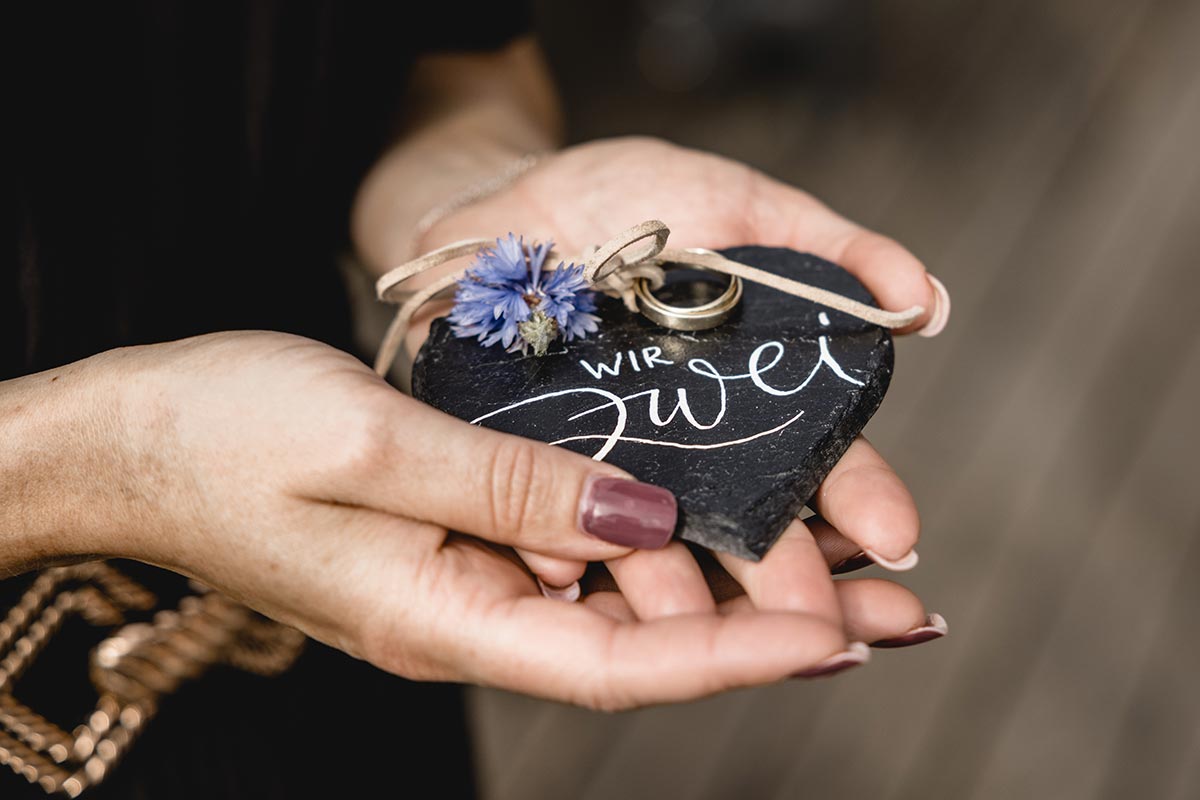 ringtafel-wir-zwei-freie-trauung-ruegen Ringtafel mit Schriftzug ‚Wir zwei‘ und Eheringen – liebevolles Detail einer freien Trauung auf Rügen