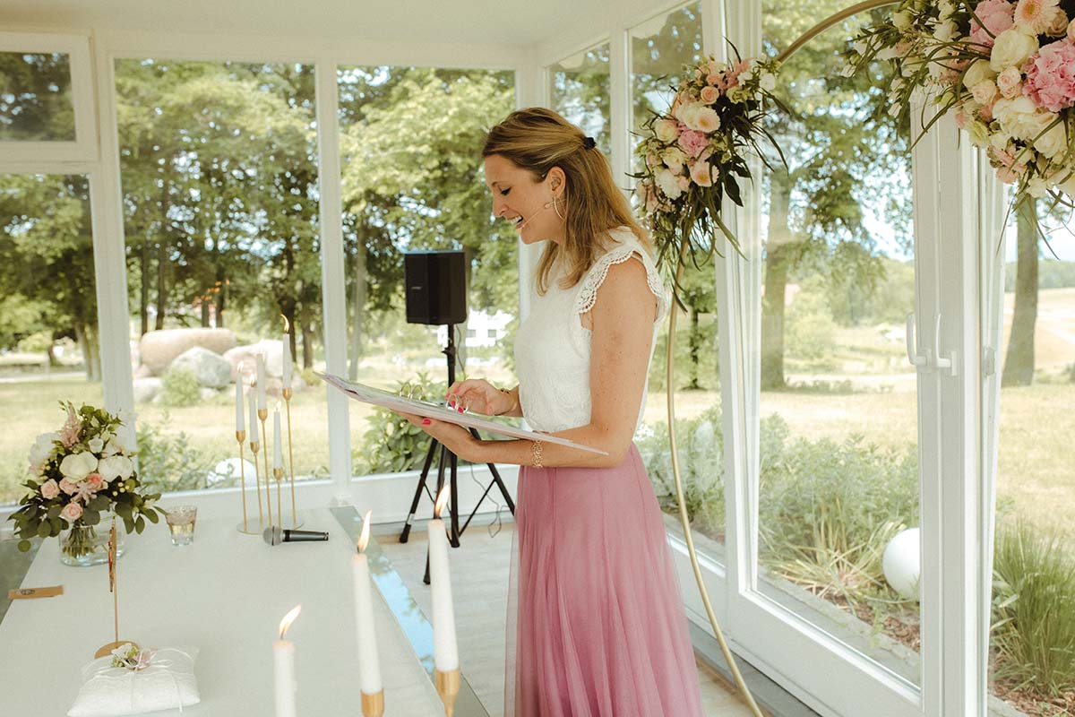 Traurednerin liest während einer freien Trauung auf Rügen im festlich geschmückten Pavillon